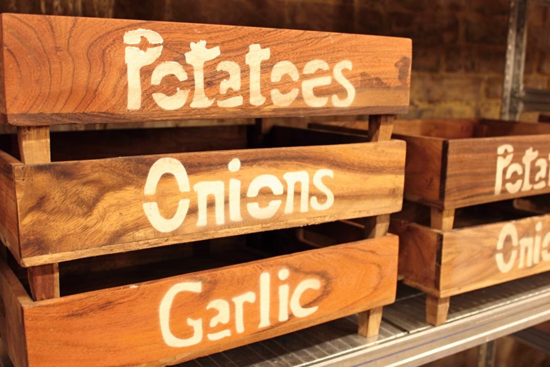 How to store potatoes and onions in separate wooden storage crates in a pantry